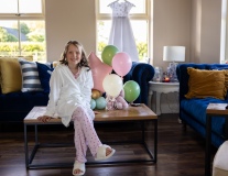 Fun portrait of Willow sitting beside balloons and her First Communion dress at home.
