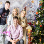 Fun and festive Christmas family portrait by Shaby Photography, capturing a smiling family in holiday attire, enjoying a playful and joyful photography session with a seasonal backdrop