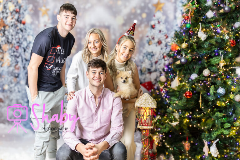 Fun and festive Christmas family portrait by Shaby Photography, capturing a smiling family in holiday attire, enjoying a playful and joyful photography session with a seasonal backdrop