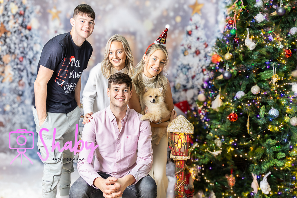 Fun and festive Christmas family portrait by Shaby Photography, capturing a smiling family in holiday attire, enjoying a playful and joyful photography session with a seasonal backdrop