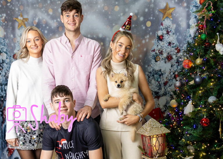 Fun and festive Christmas family portrait by Shaby Photography, capturing a smiling family in holiday attire, enjoying a playful and joyful photography session with a seasonal backdrop