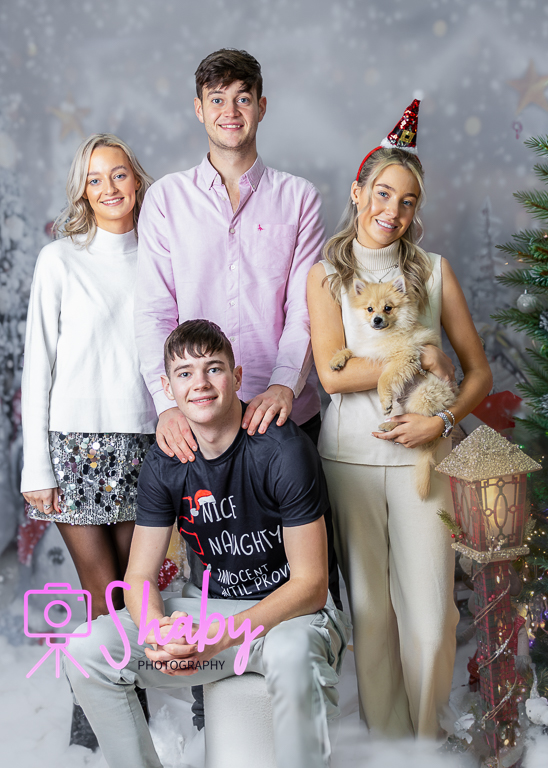 Fun and festive Christmas family portrait by Shaby Photography, capturing a smiling family in holiday attire, enjoying a playful and joyful photography session with a seasonal backdrop