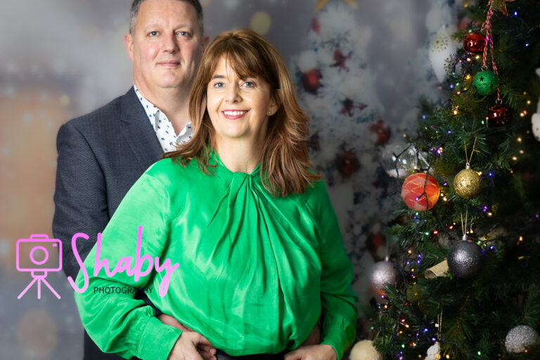 Fun and festive Christmas family portrait by Shaby Photography, capturing a smiling family in holiday attire, enjoying a playful and joyful photography session with a seasonal backdrop