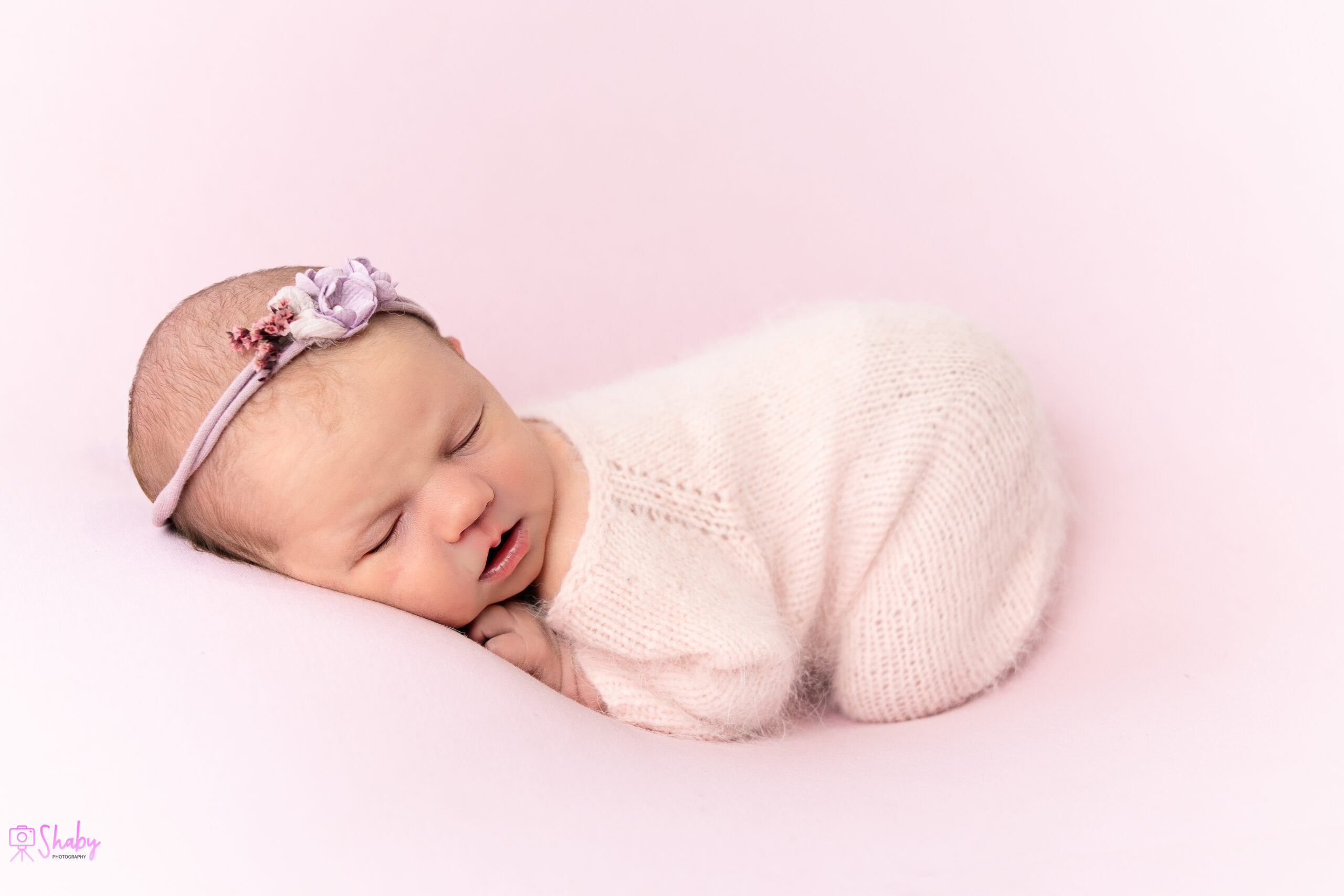 Newborn baby girl Nora sleeping peacefully with a gentle smile, during a professional photography session in Ireland.