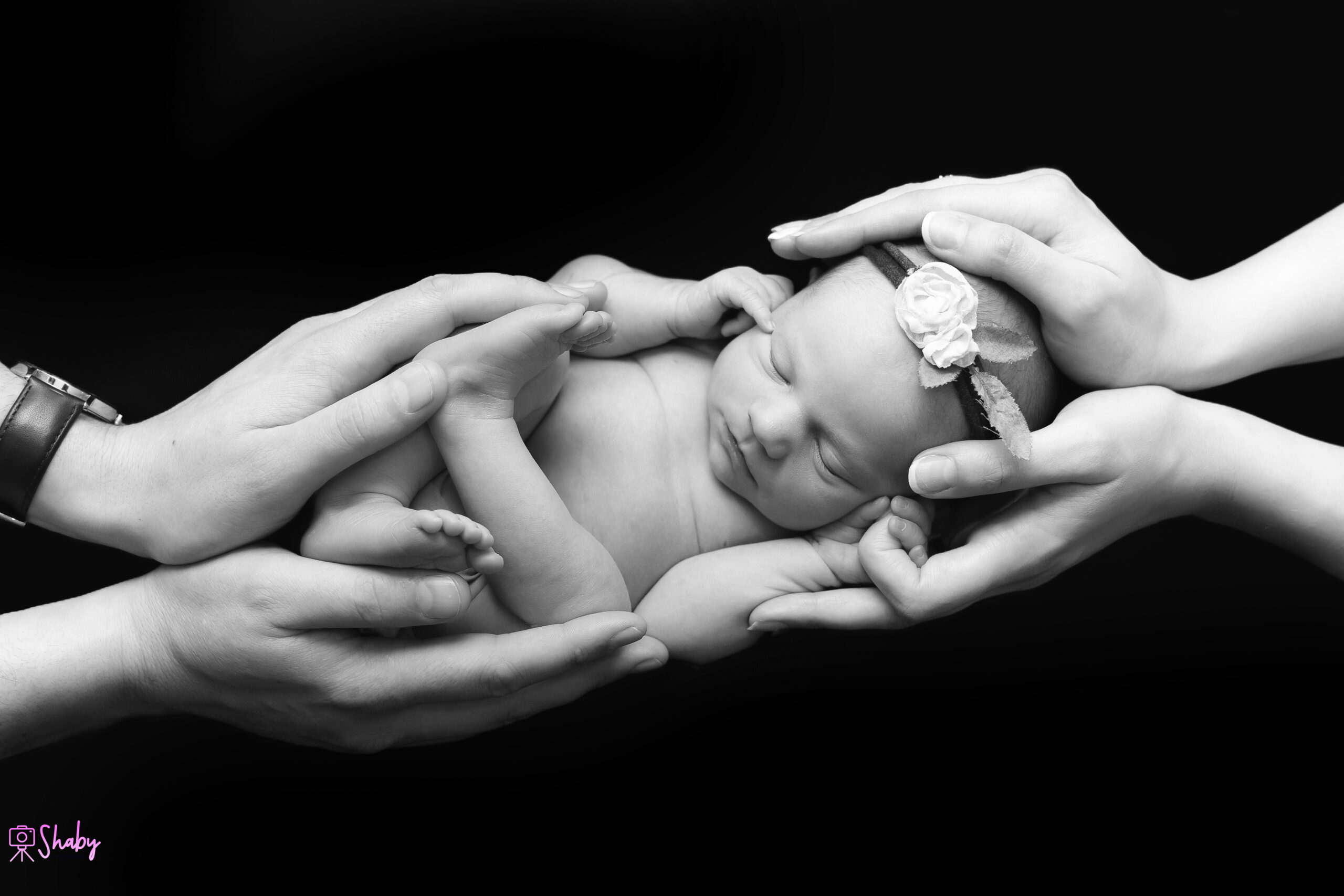 Newborn baby girl Nora sleeping peacefully with Mam and Dad holding her lovingly, during a professional photography session in Ireland.