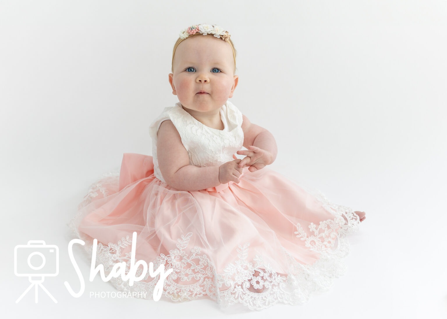 5-month-old baby girl in a beautiful dress posing comfortably for newborn photography in Ireland, taken by Shaby.ie a newborn and childrens photographer based in Meath