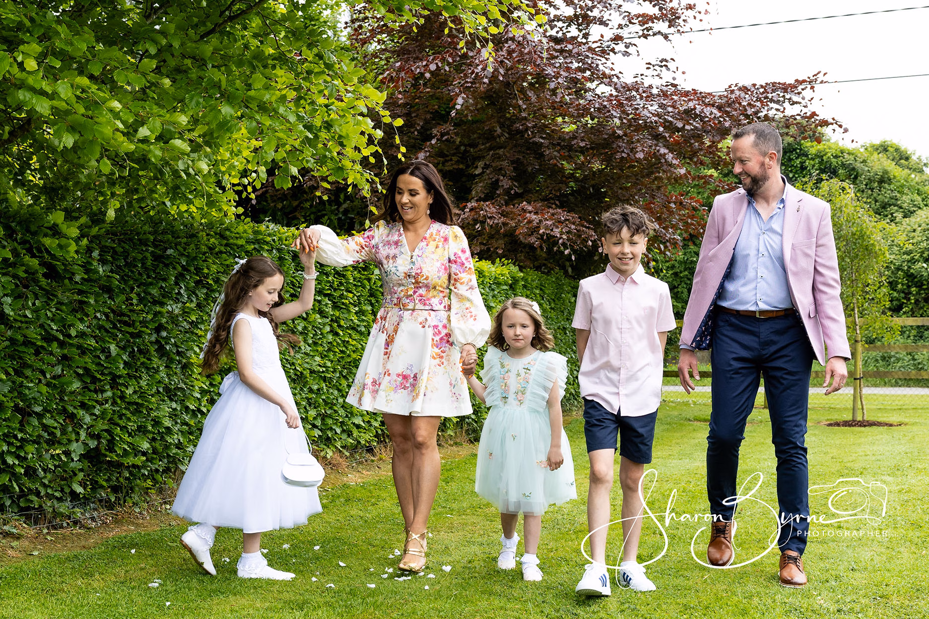 Family portrait photographer - family casually walking in their garden on first holy communtion day