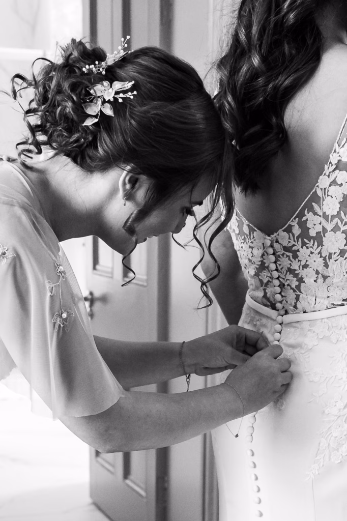Photo Gallery - Photo of Edel the beautiful and relaxed Bride, being buttoned up by her gorgeous niece and maid of Honour - Emily.