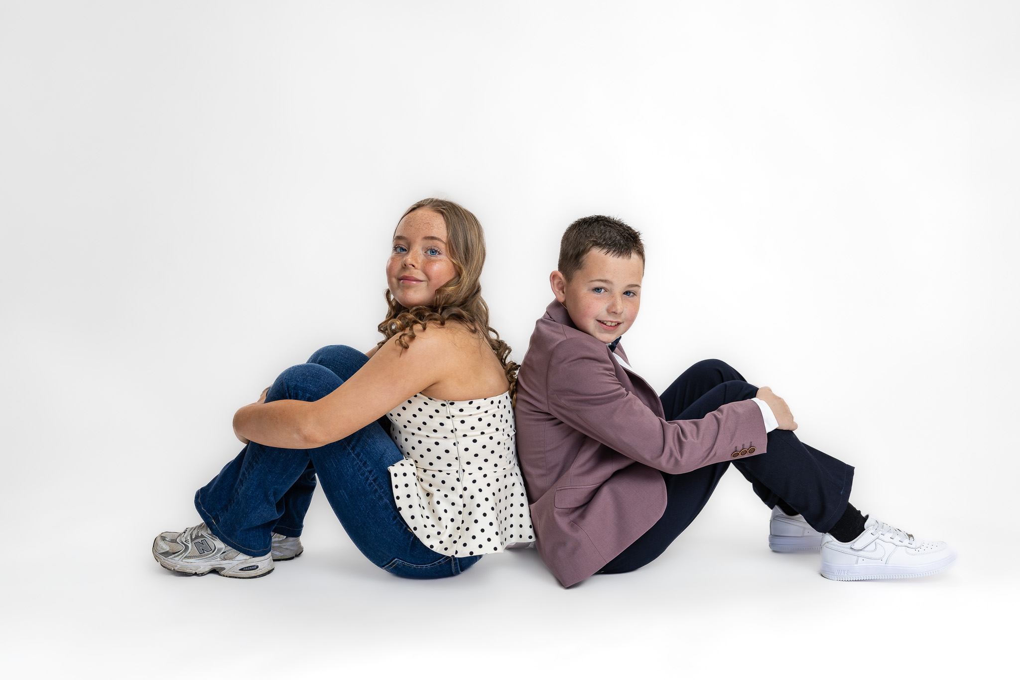 Relaxed seated portrait of Charlie and his sister Grace photographed during a modern family studio session in Ireland.