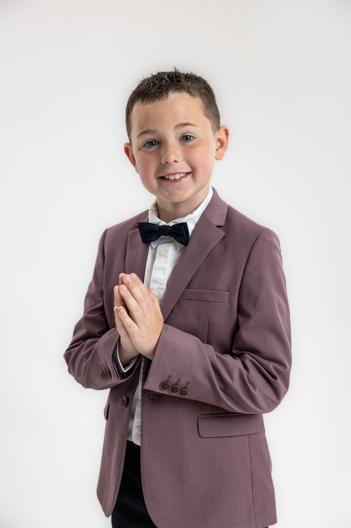 Natural studio portrait of a young boy in a mauve jacket during a relaxed family portrait session near Dublin.
