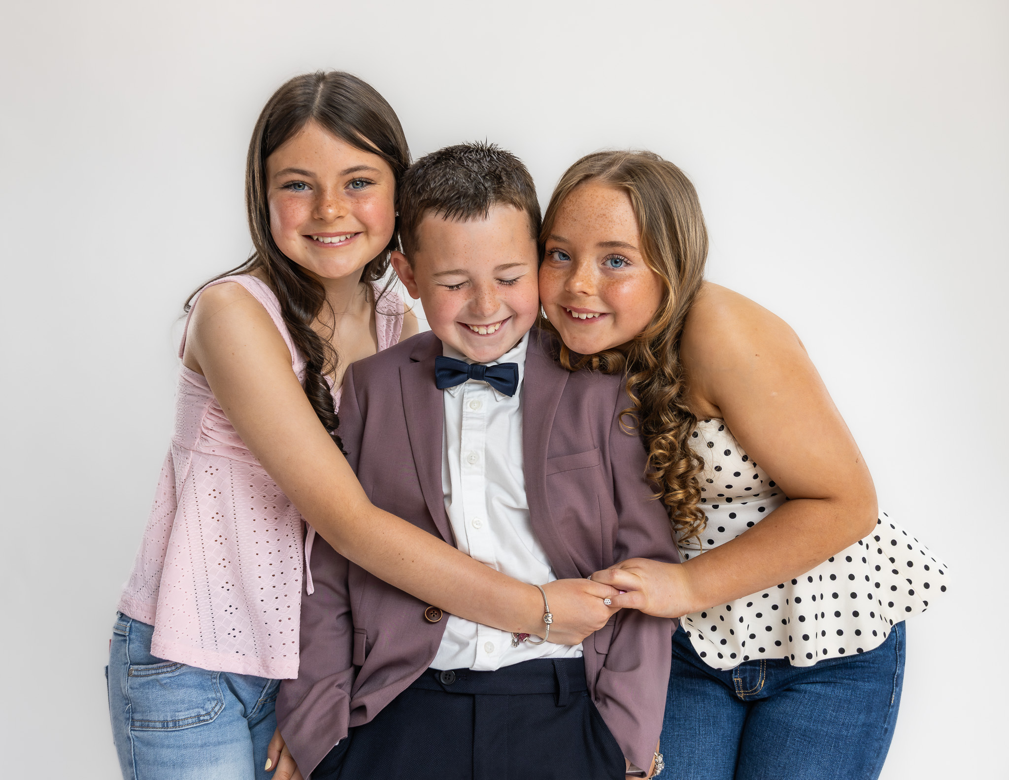 Relaxed family studio portrait with sister and cousing hugging Charlie during a modern family photography session in Ireland.