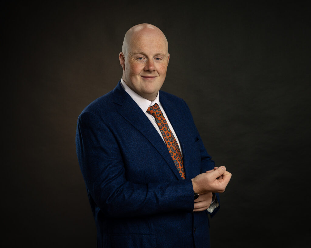 Professional headshot of Ross in a navy suit, a confident studio portrait taken near Dublin