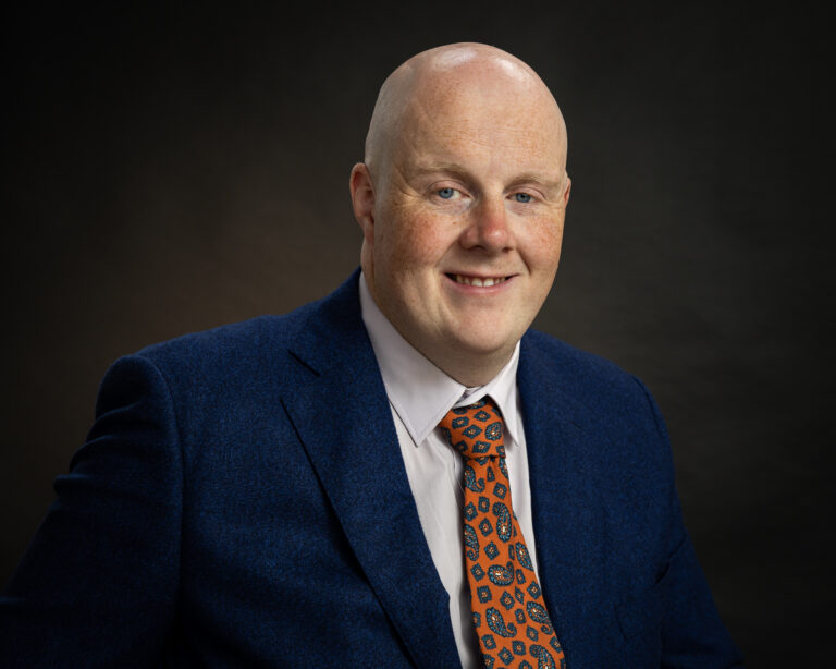 Warm, smiling professional headshot of Ross taken in a relaxed studio session near Dublin