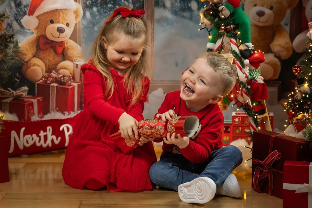 Little boy laughing as his sister opens a Christmas cracker in a Kilcock photography studio